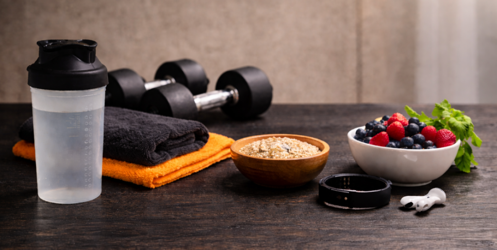 Fitness und Ernährung mit dunklen Hanteln, Shaker und Obst auf schwarzem strukturiertem Tisch