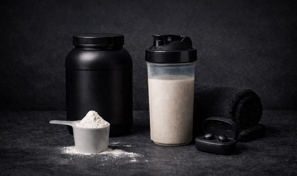 Eiweißshake, Proteinpulver und Trainingszubehör zur Regeneration nach dem Hybridtraining aus Lauf- und Krafttraining.